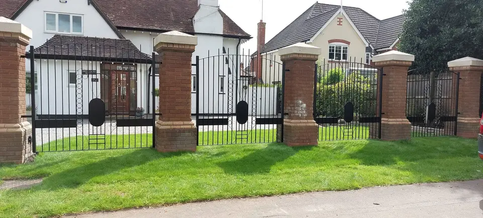 Black bar railings between brick piers with stone caps along a front lawn