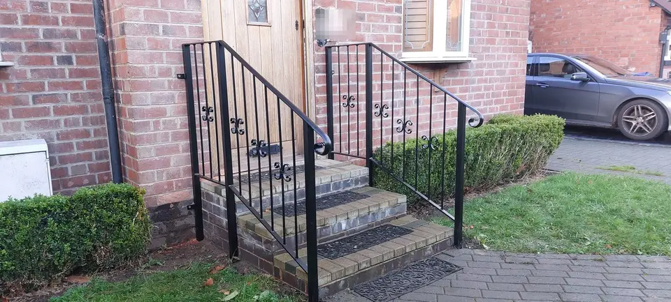 Pair of black handrails with scroll details either side of three brick front steps