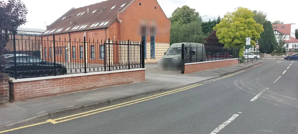 Black scroll-topped railings on a low brick wall beside a quiet road