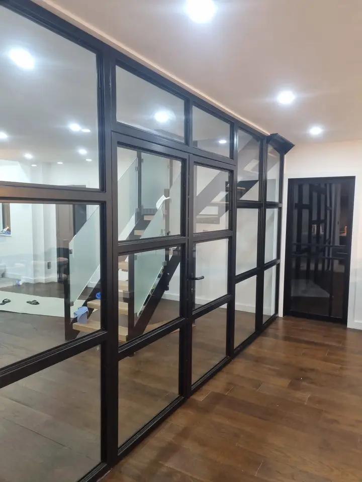 Finished black steel and glass partition running along a hallway with a wood floor
