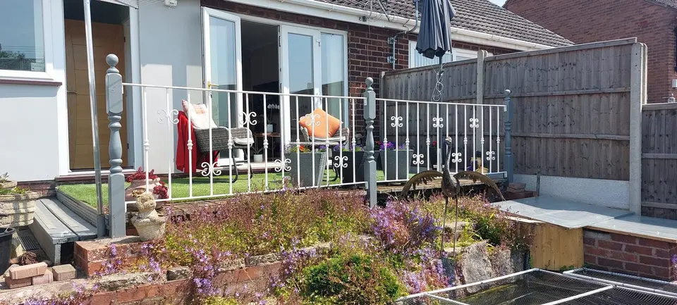 White painted steel railings with scroll details around a raised terrace, with turned corner posts