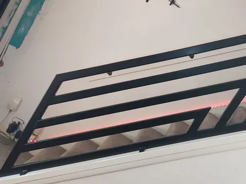 Black geometric balustrade above a staircase with a pink LED strip along the skirting