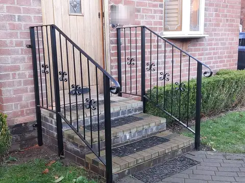 Pair of black handrails with scroll details either side of three brick front steps