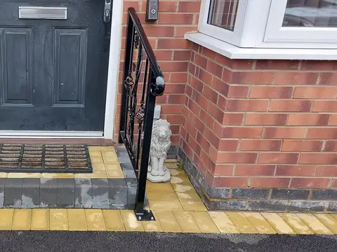 Black handrails with scroll details on both sides of a small front step, stone lions at each end