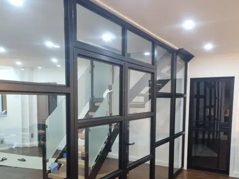 Finished black steel and glass partition running along a hallway with a wood floor