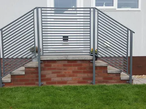 Grey painted steel balustrade with horizontal bars around a set of front steps