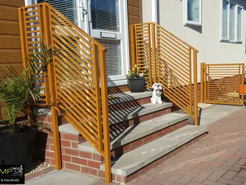 Orange steel handrails and a matching gate with horizontal slats beside front steps