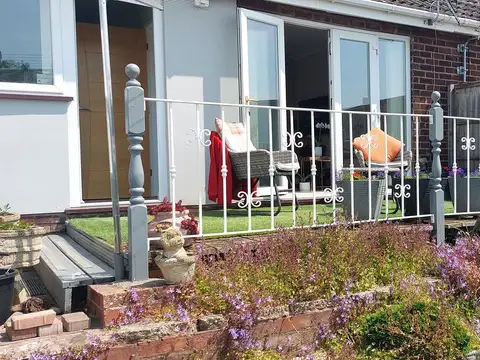 White painted steel railings with scroll details around a raised terrace, with turned corner posts